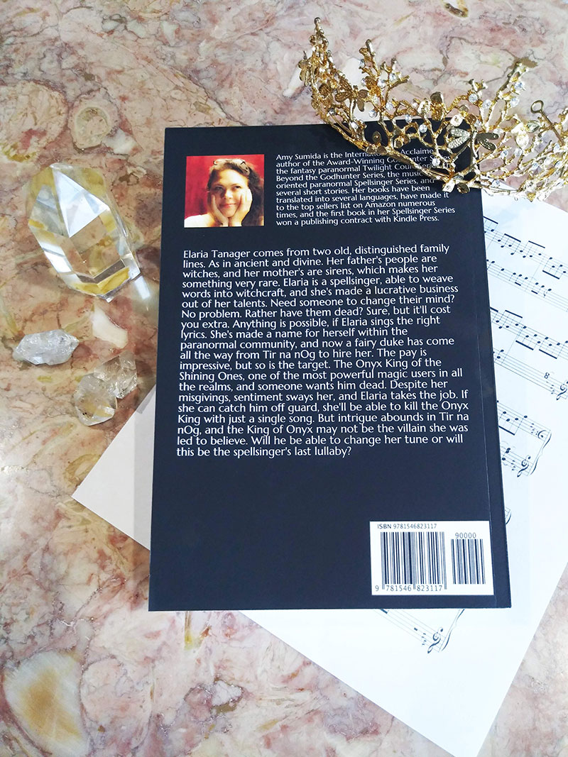 Back cover of Last Lullaby sitting on a music score with crystals and a crown